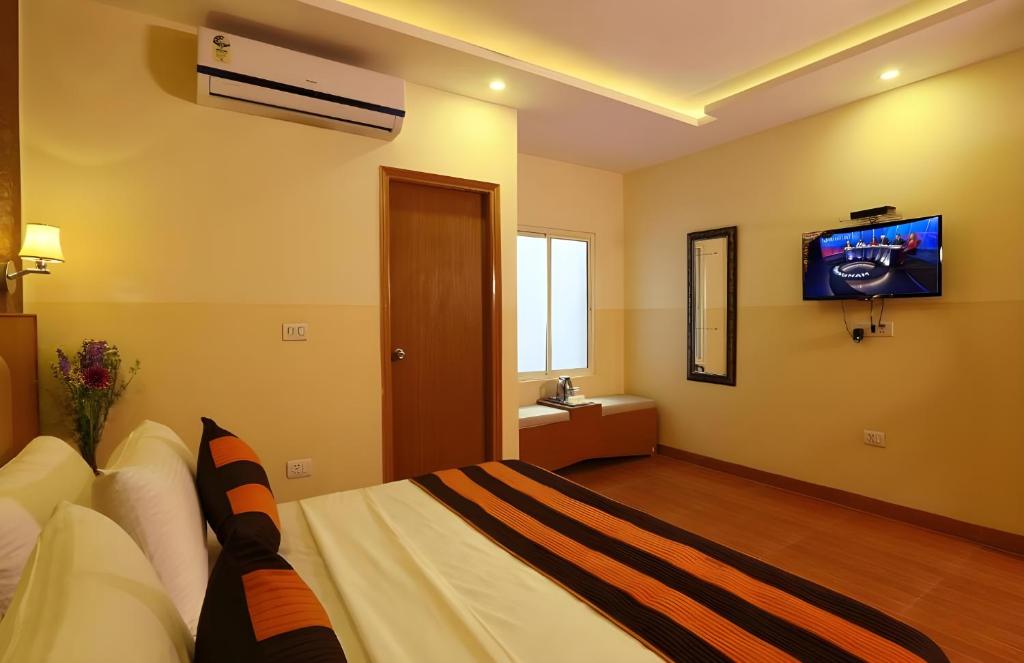 新德里Hotel Aeroporto Near By Delhi International Airport的卧室配有一张床铺,墙上配有电视