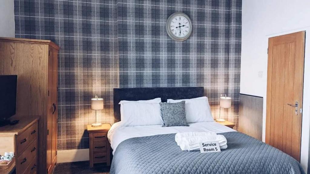 滕比克罗尔兰德宾馆的卧室配有一张挂在墙上的带时钟的床