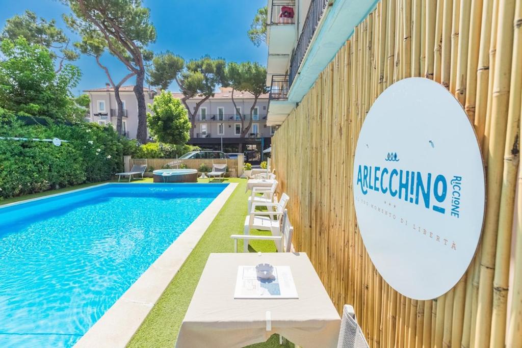 里乔内Hotel Arlecchino Riccione的游泳池旁墙上的标志