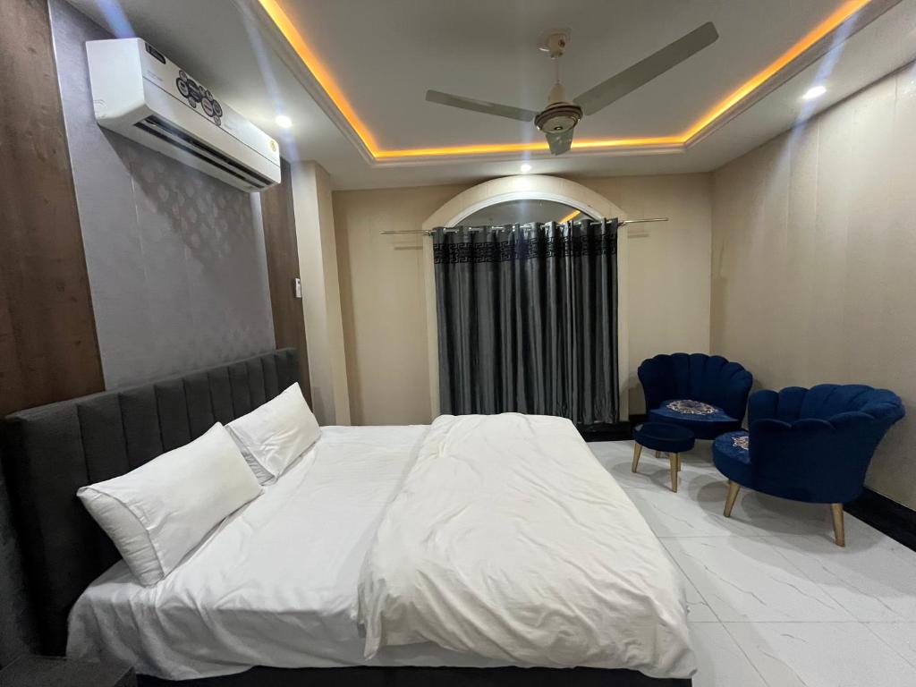 KhāriānKharian-Inn Hotel的一间卧室配有白色的床和2把蓝色的椅子