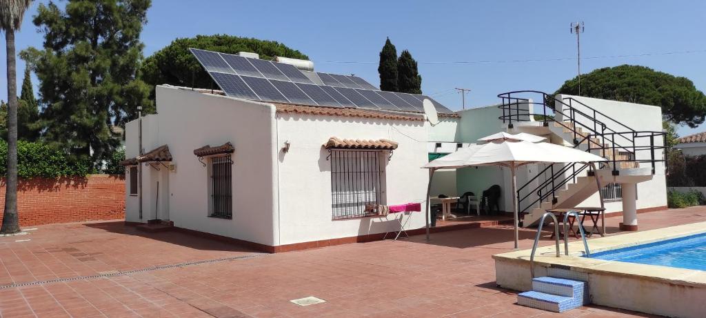 圣玛丽亚港Chalet Valdelagrana的屋顶上设有太阳能电池板的房子,毗邻一个游泳池