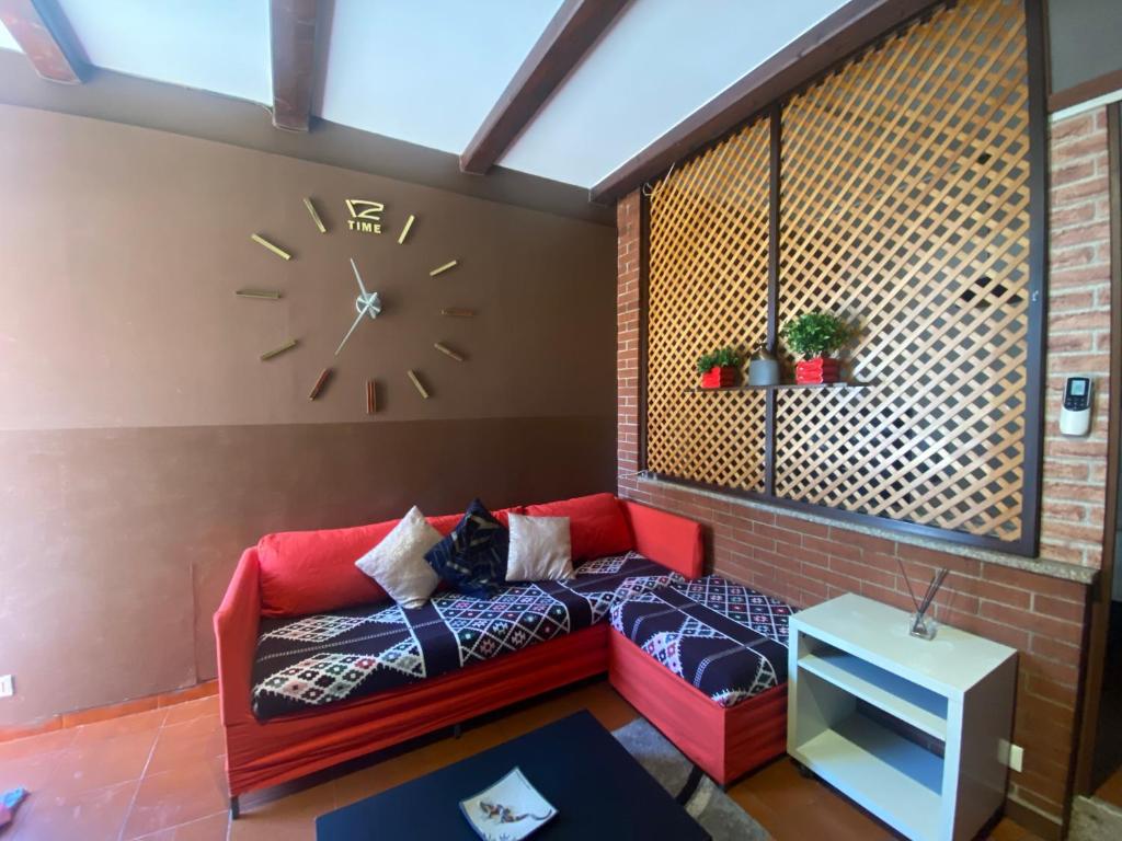 比耶拉Appartamento Homemade的客厅配有红色的沙发和墙上的时钟