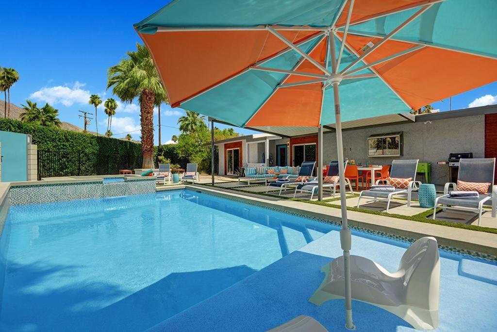 棕榈泉Shelby Sands的一个带遮阳伞和椅子及桌子的游泳池