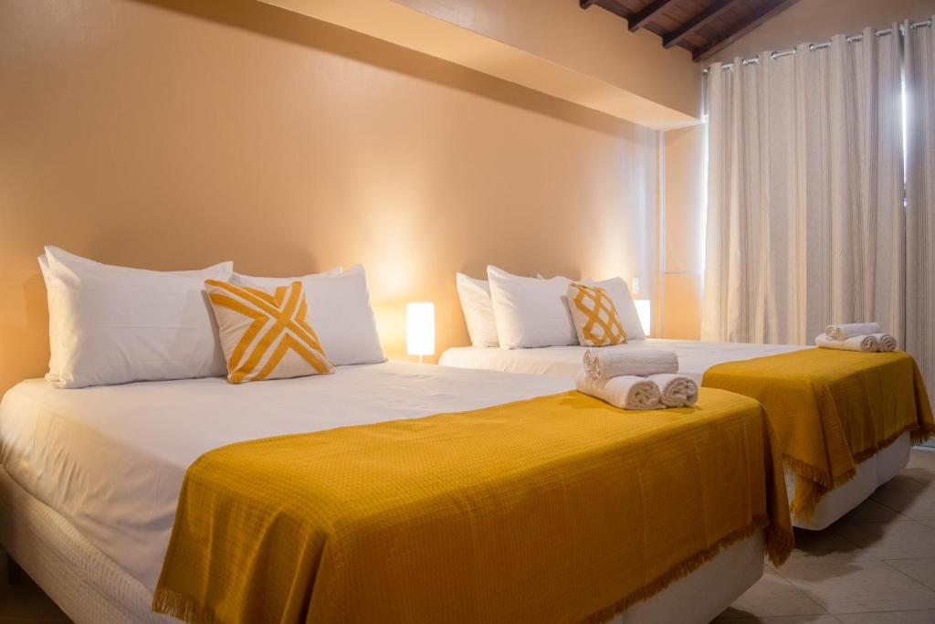 布希奥斯Porteño Loft Búzios的配有黄色床单的客房内的两张床