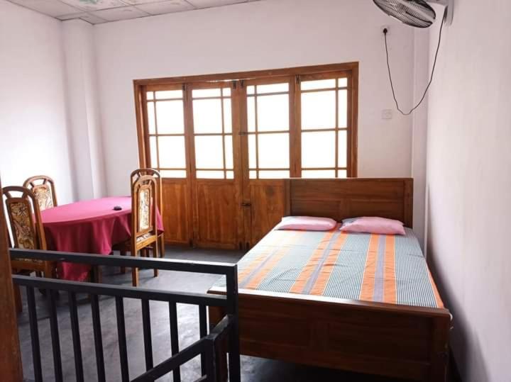 阿努拉德普勒Puraya'S Lodge的一间卧室配有一张床、一张桌子和一个窗户。