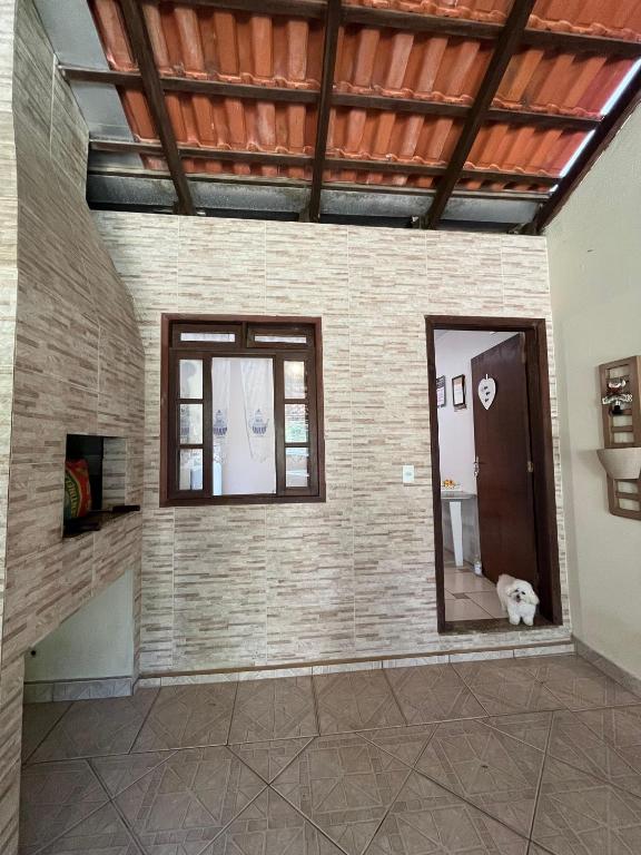 布卢梅瑙Casa com suíte的一间设有两扇窗户的客房和一只狗坐在地板上