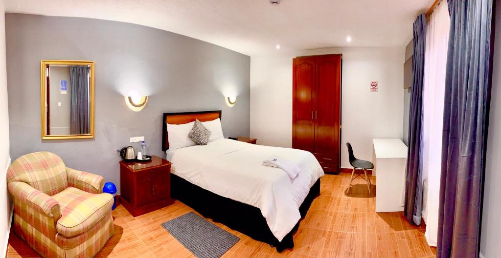 伊瓦拉Quinta San Carlos Hostel的配有一张床和一把椅子的酒店客房