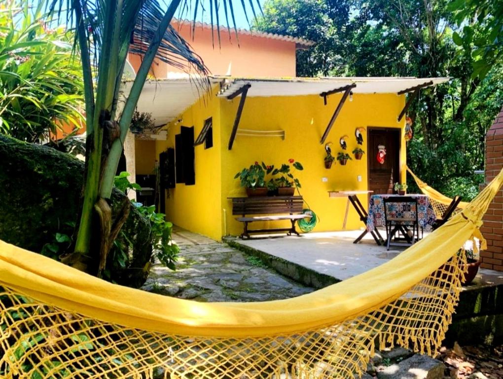 伊利亚贝拉Chalé da cachoeira - Ilhabela的黄色房子前面设有吊床