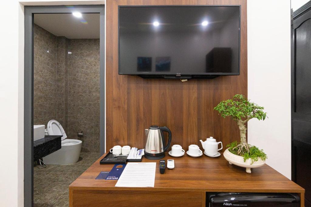 Trảng BàngGems Hotel - Khách sạn Trảng Bàng的墙上的电视机,浴室里,有桌子
