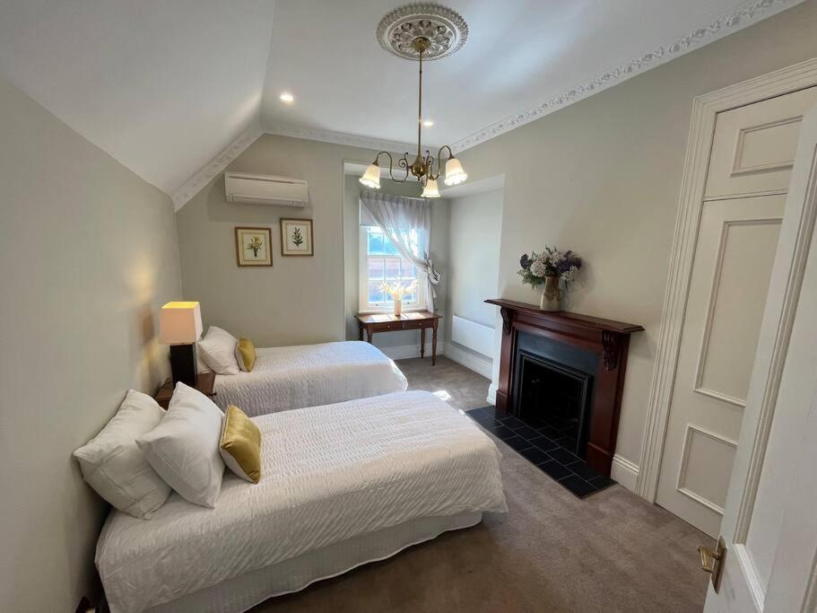 奥尔伯里Porters Cottage Oasis的一间卧室设有两张床和一个壁炉