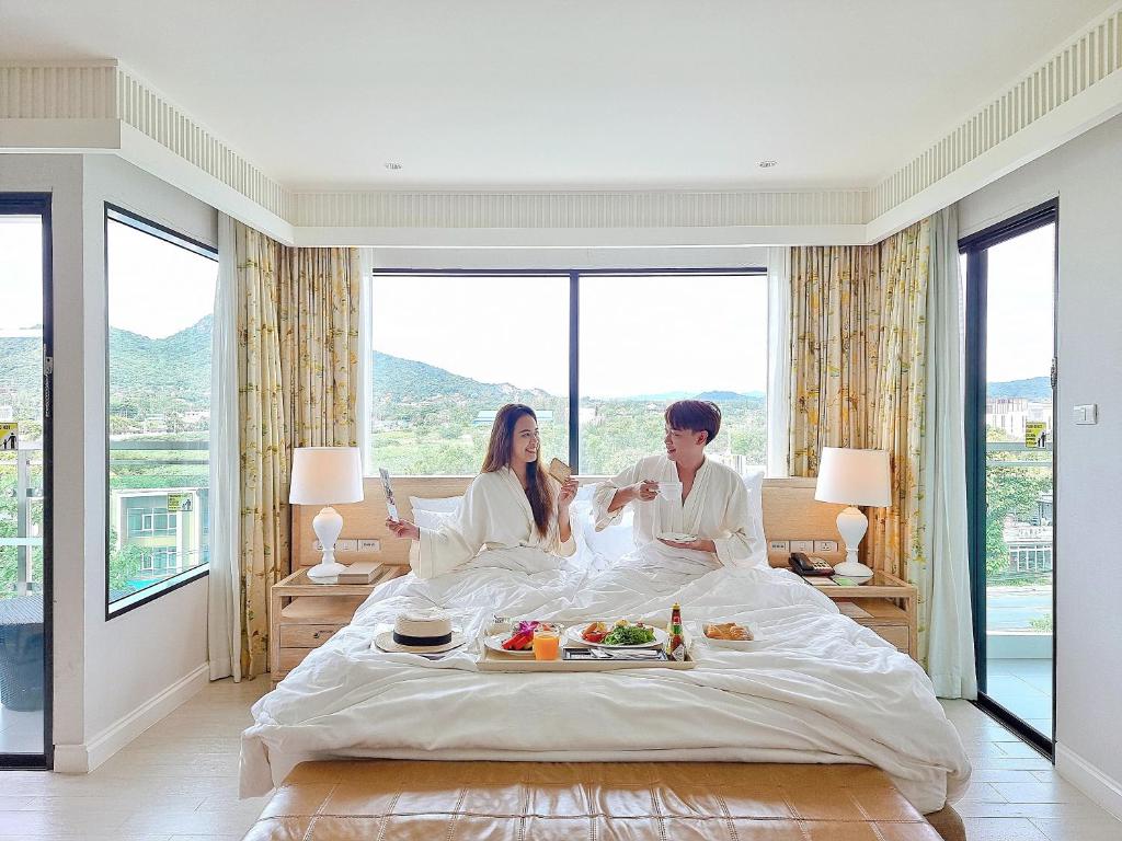 华欣华欣阿玛瑞度假酒店的坐在酒店房间床上的男女