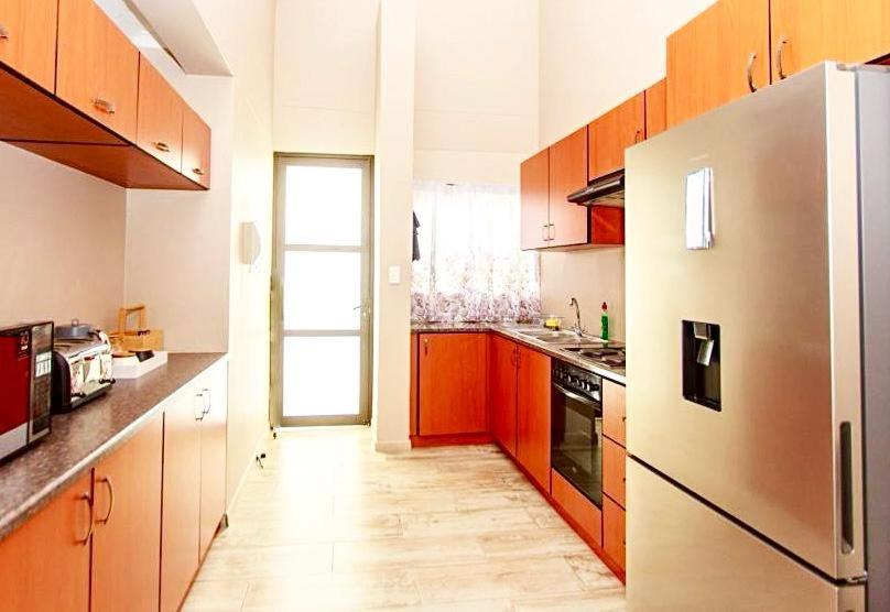 OngwedivaMorningSide Fortyfive的厨房配有木制橱柜和冰箱。