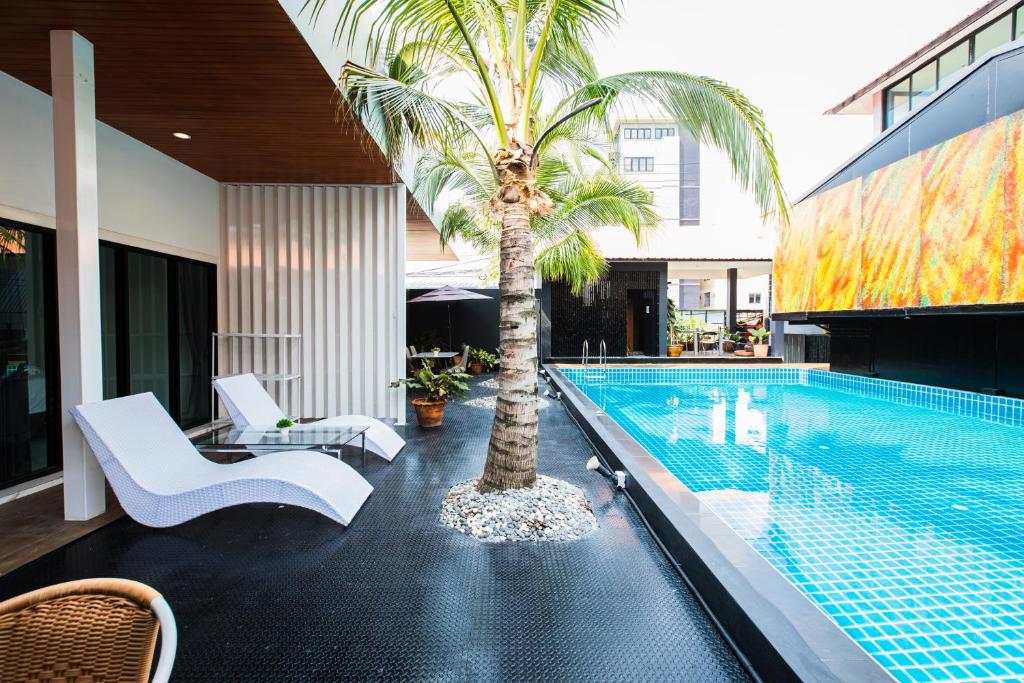 巴吞他尼PP@Hotel Rangsit的一座房子旁的游泳池,里面种着棕榈树