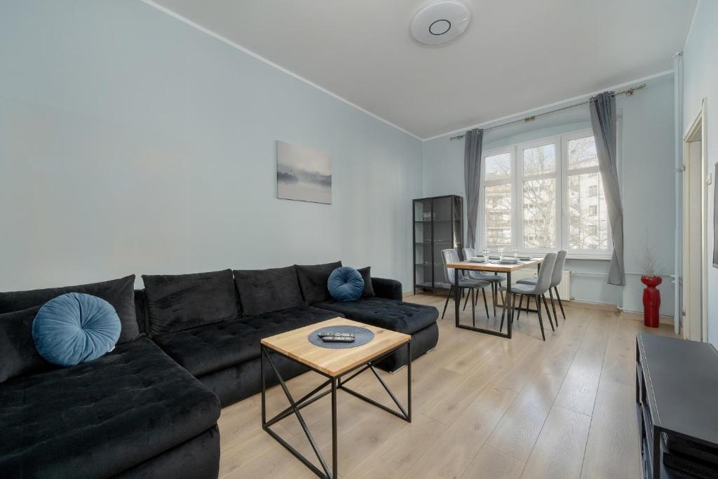 弗罗茨瓦夫Spacious 3-Bedroom Apartment Plac Grunwaldzki Wrocław by Renters的客厅配有黑色沙发和桌子