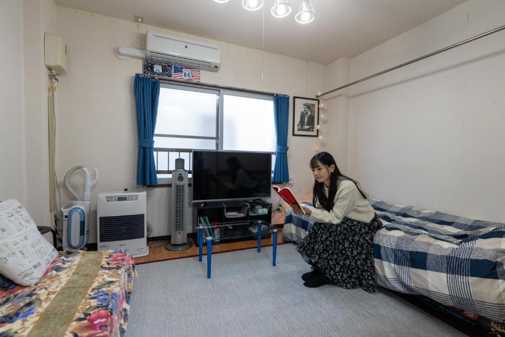 札幌ALMAZ PLACE #203的坐在床上读书的女人