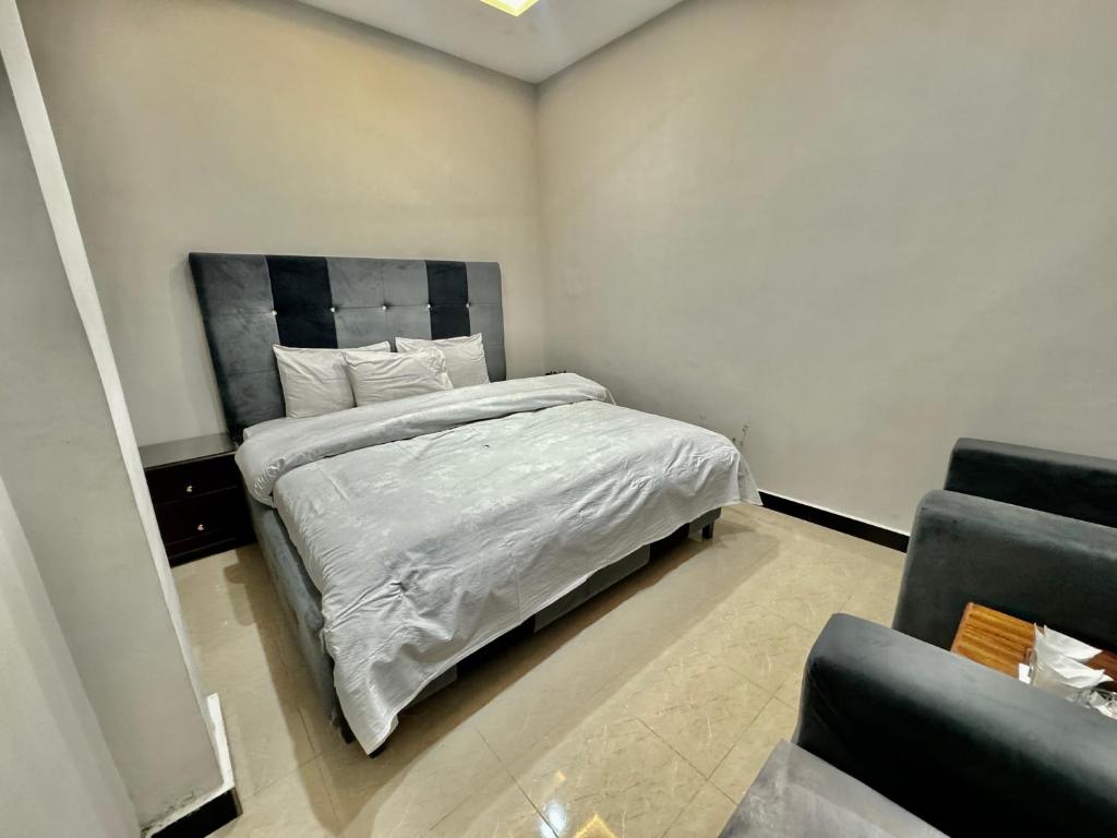 伊斯兰堡Al Atif Hotel的一间卧室配有一张带白色床单和椅子的床
