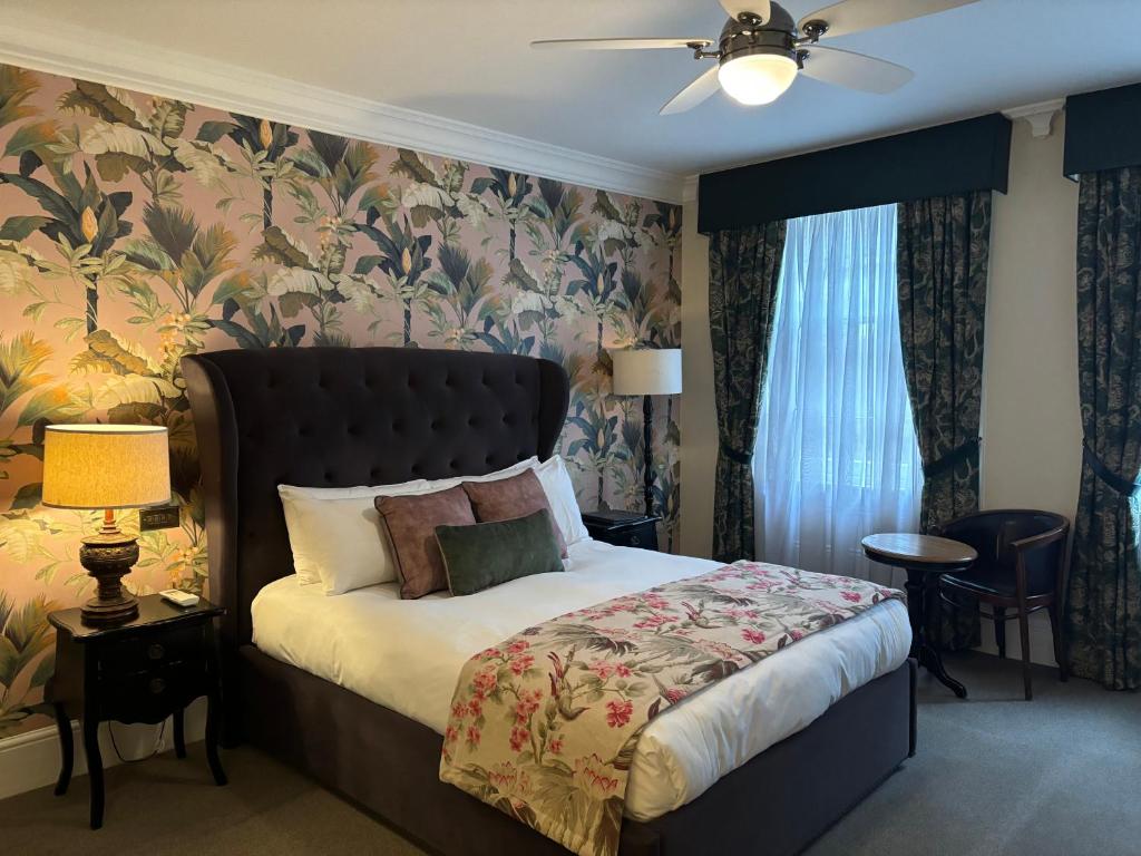 伦敦柯乐克优质酒吧和客房酒店的一间卧室配有一张带花卉壁纸的床