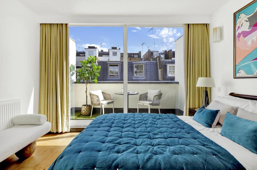 伦敦3 bdrm Notting Hill Mews house - 2 balconies的卧室设有一张蓝色大床和大窗户