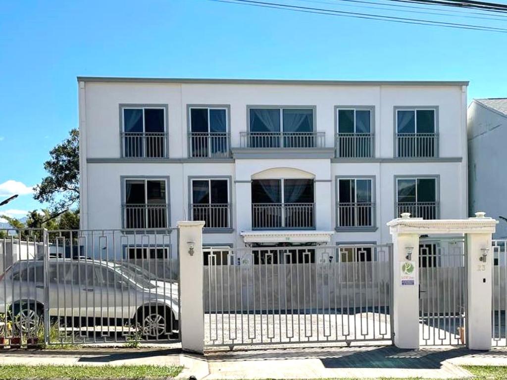 Ciudad CariariLOP Inn San Jose Aeropuerto - Costa Rica的前面有带围栏和汽车的白色房子