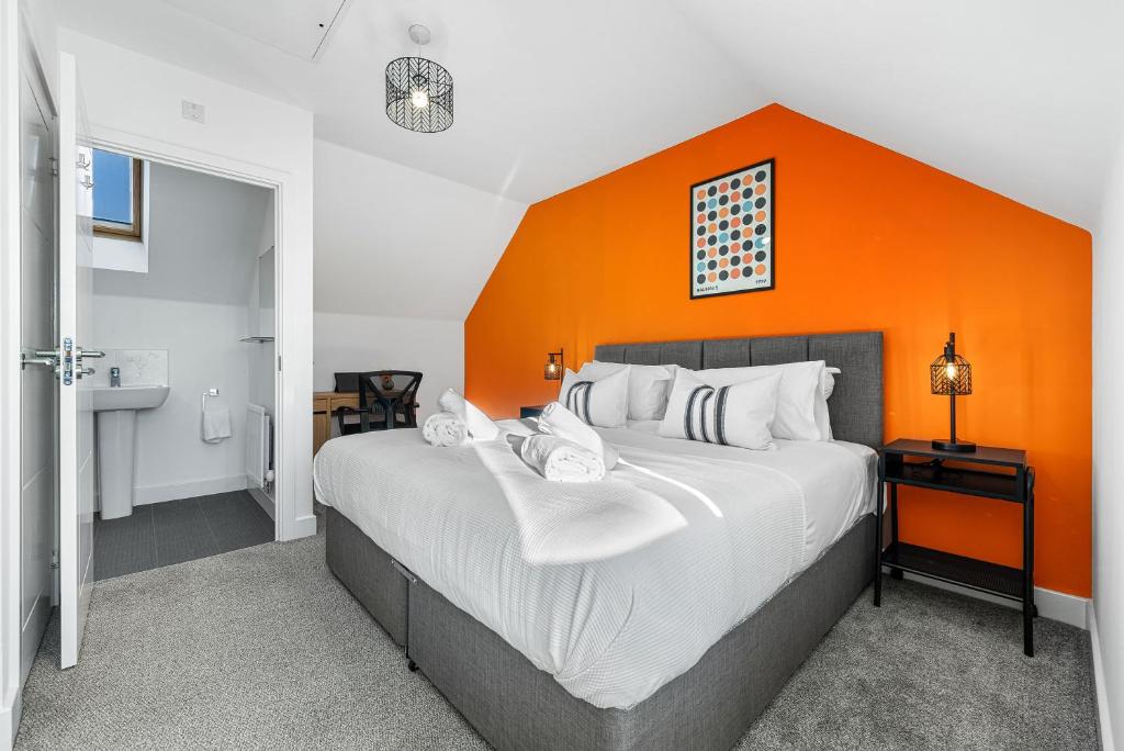 格洛斯特Stylish 4-Bedroom Townhouse with two large parking spaces and superfast Wi-Fi的一间卧室配有一张带橙色墙壁的大床