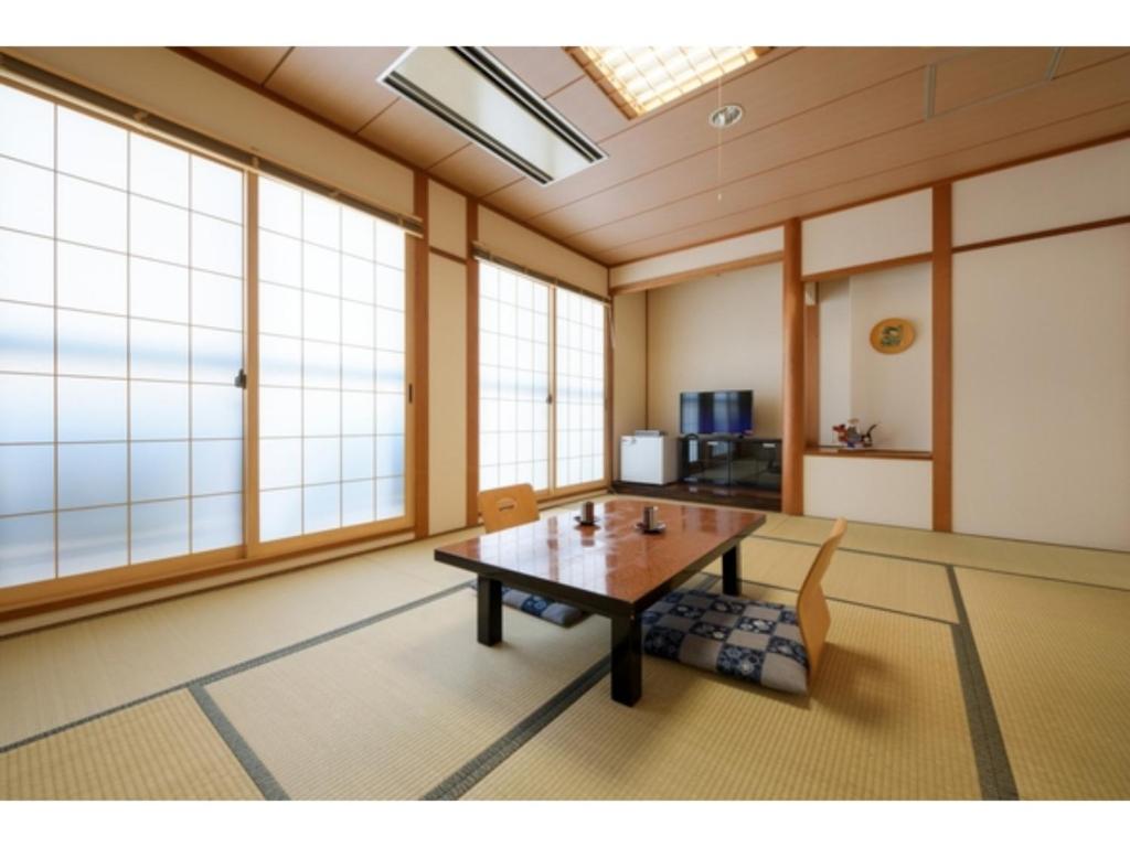 十和田Towada City Hotel - Vacation STAY 85233v的客房设有桌椅和窗户。