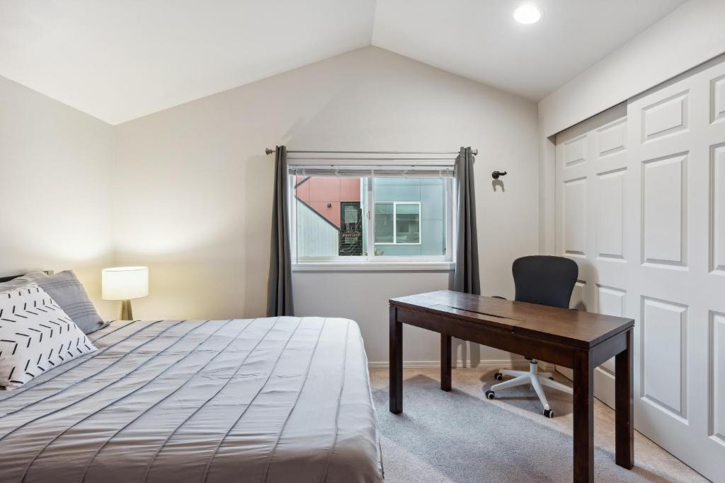 西雅图2BR Seattle Oasis - A Short Stroll to Light Rail的一间卧室配有一张床、一张书桌和一个窗户。