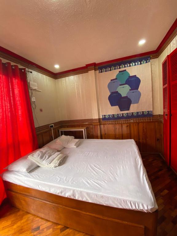 碧瑶Casa Valle Verde的一间卧室配有白色床单和红色窗帘