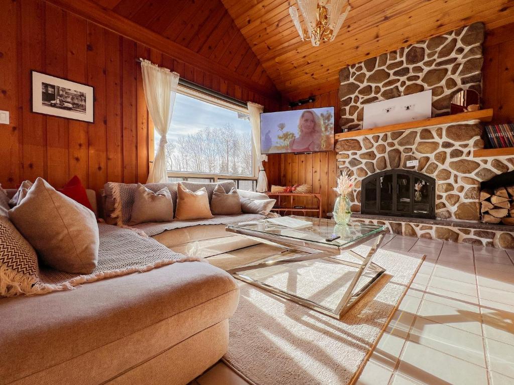 圣阿黛拉Luxury St-Sauveur Chalet with Swim Spa Close to Ski的带沙发和石制壁炉的客厅