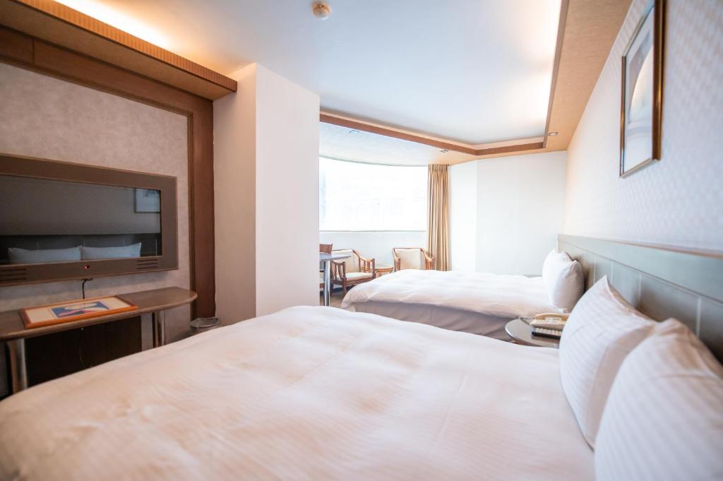 台中市台中灣文旅 T C ONE Hotel的酒店客房设有两张床和一台平面电视。