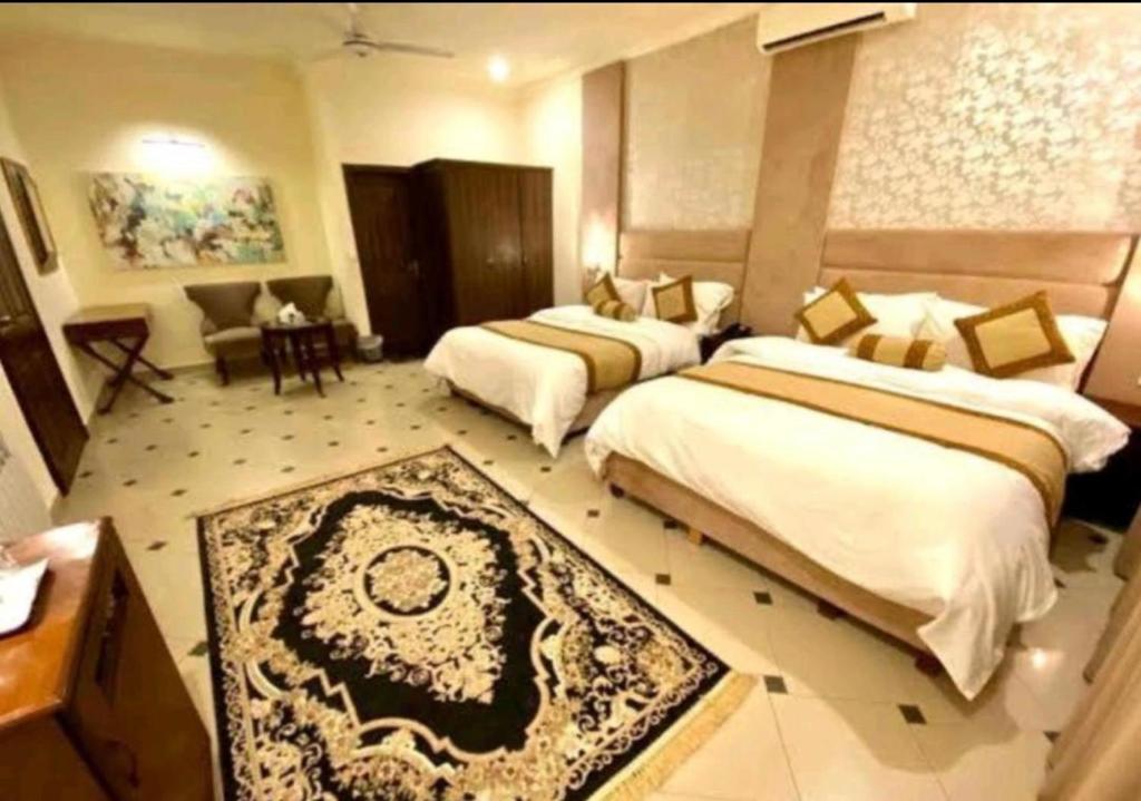 伊斯兰堡Imperial Lodges的酒店客房带两张床和一张桌子以及椅子。