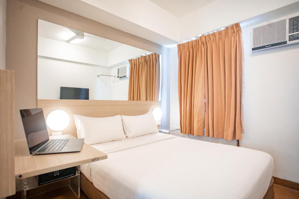 马尼拉Red Planet Makati Avenue Manila的一间卧室配有一张床铺,书桌上配有一台笔记本电脑