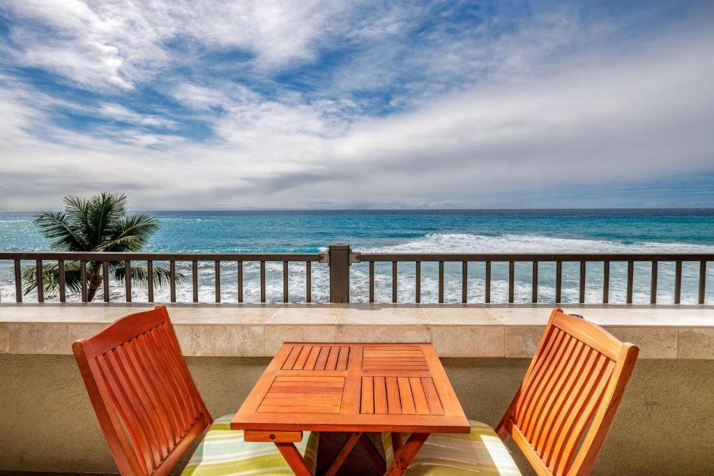科纳悦榕庄404D度假屋的阳台配有一张桌子和两把椅子,享有海景