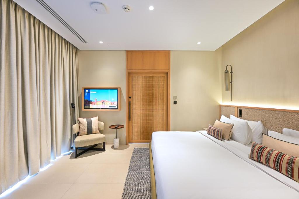 沙迦Al Badayer Retreat by Sharjah Collection的配有一张床和一把椅子的酒店客房