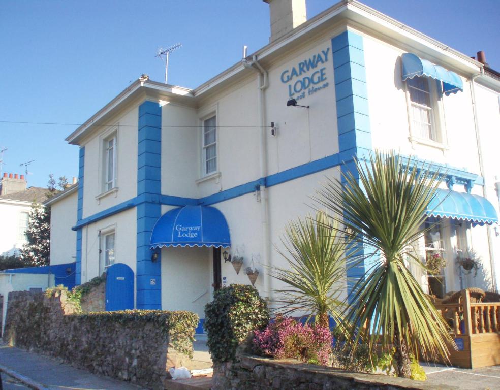 托基Garway Lodge Guest House的白色和蓝色的建筑,前面有棕榈树