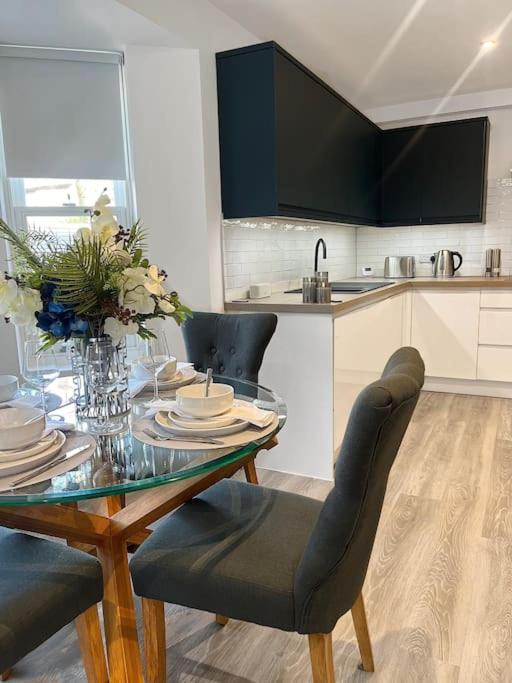 沃辛Luxury 3 Bedroom House的厨房配有玻璃桌、椅子和桌子。