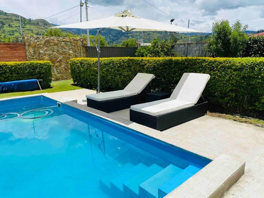 PauteAlegre villa con piscina para uso familiar de 3 dormitorios的一个带2把躺椅和遮阳伞的游泳池