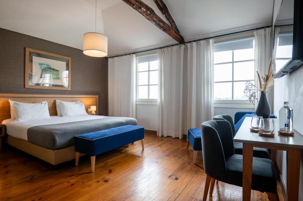 波尔图Santa Catarina FLH Suites的酒店客房带一张床、一张桌子和椅子