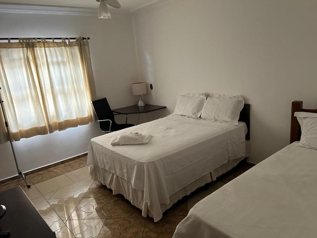 圣若泽杜斯坎普斯Quarto com / Bosque / Estoril / SJC的一间卧室设有两张床、一张桌子和一个窗口