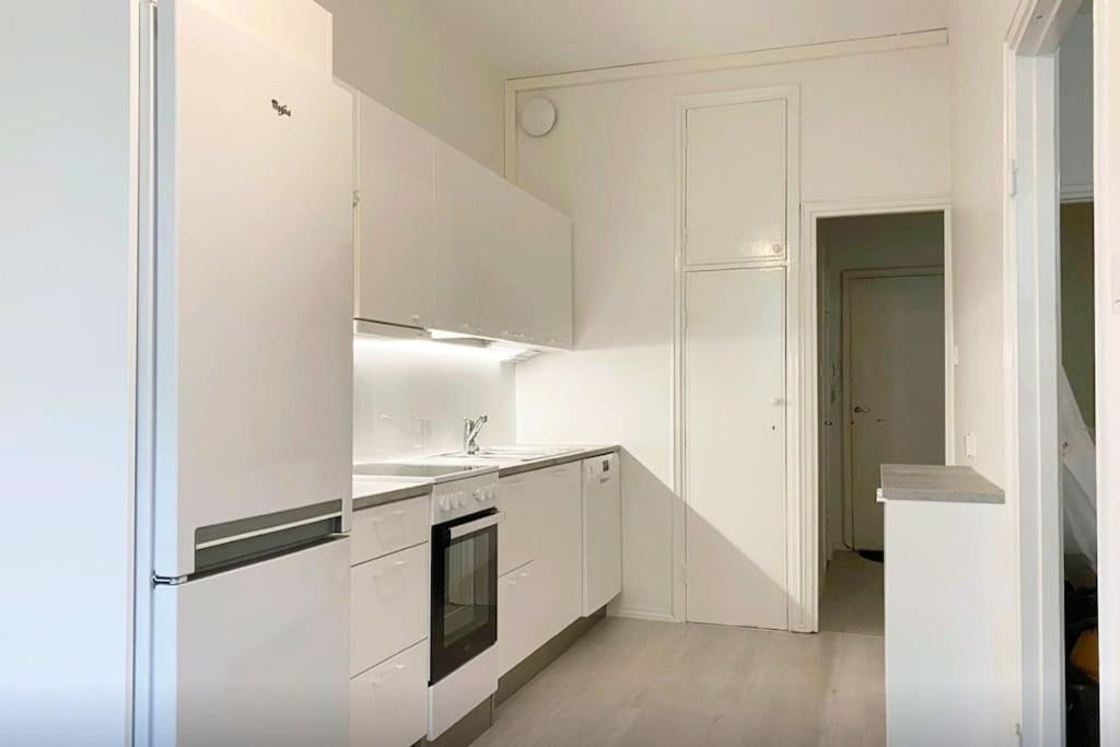 赫尔辛基Moderni siisti Studio koti jossa modernit kalusteet的白色的厨房配有水槽和冰箱