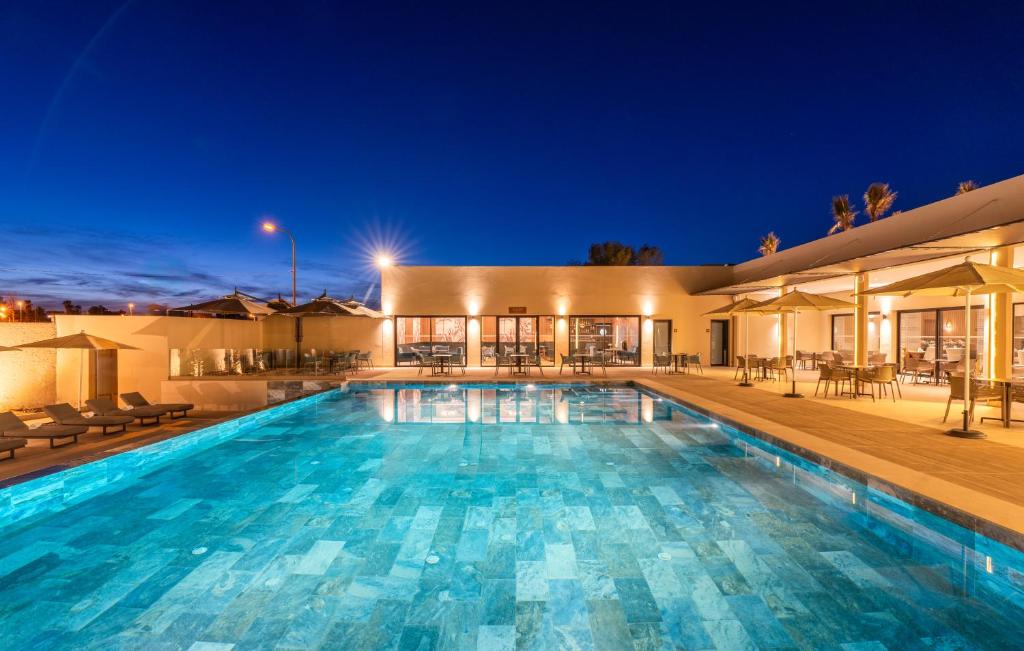 拉希迪耶肯兹日萨尼酒店的一座大型游泳池,在晚上在房子前面