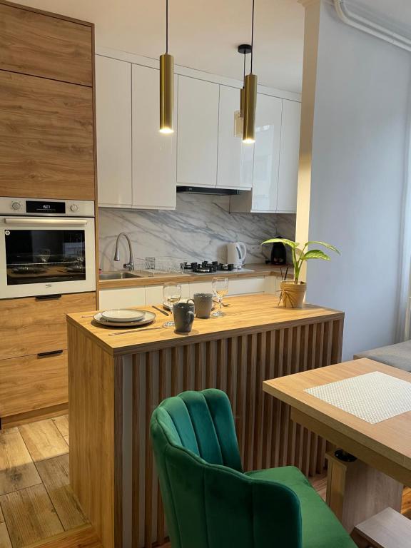 蒂黑Apartament Żwakowska的厨房配有白色橱柜和带绿色椅子的木制岛屿