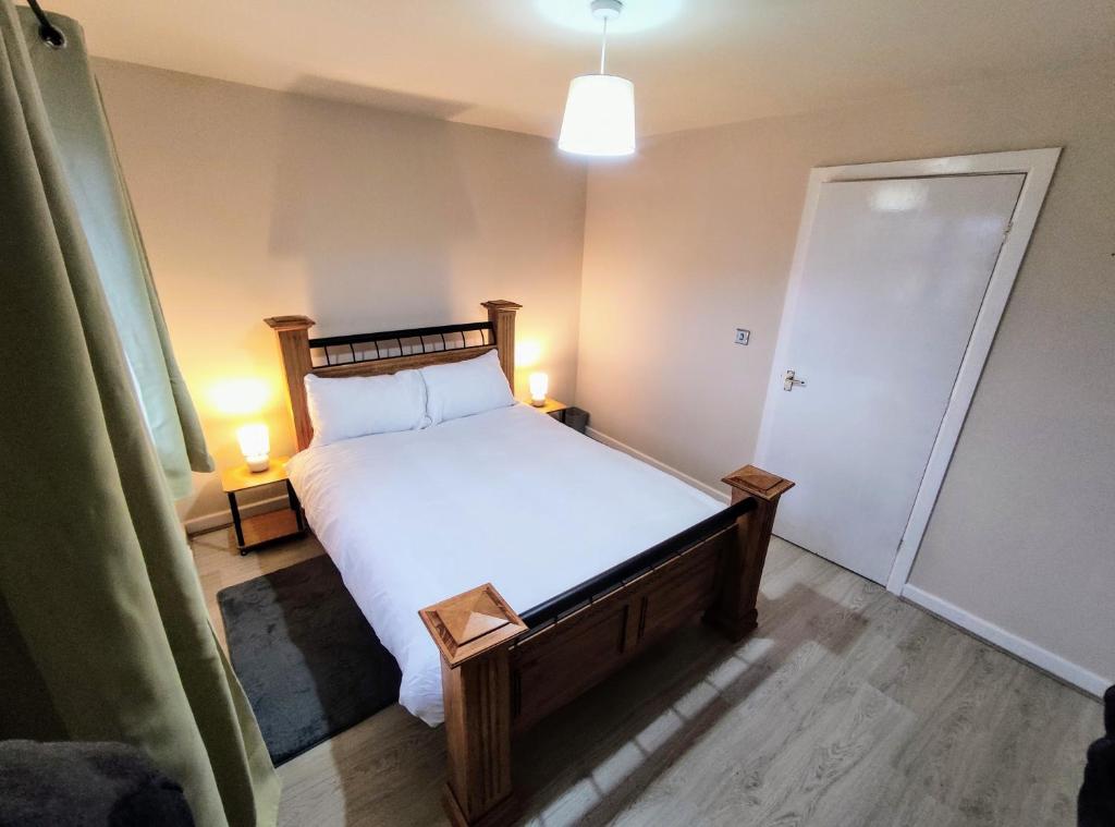 IdleHigh Rigg House Bradford - Luxury Accomodation with Private Parking的一间卧室配有一张带白色床单和两盏灯的床。