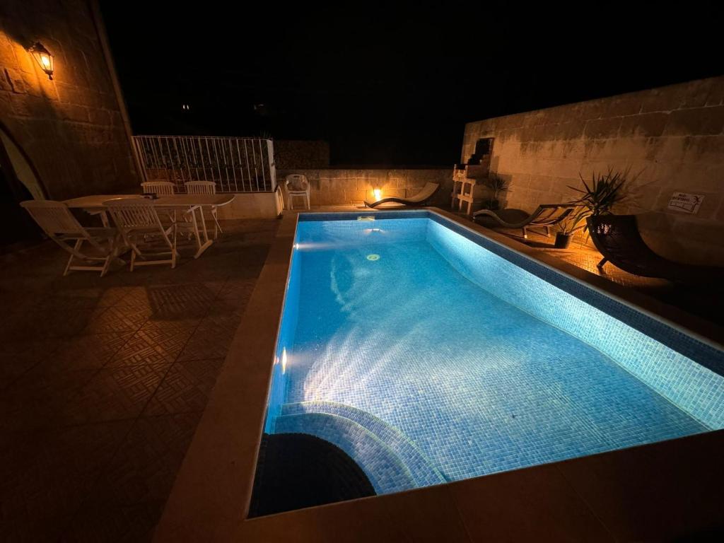 维多利亚Tal-Kaptan的游泳池在晚上配有桌椅