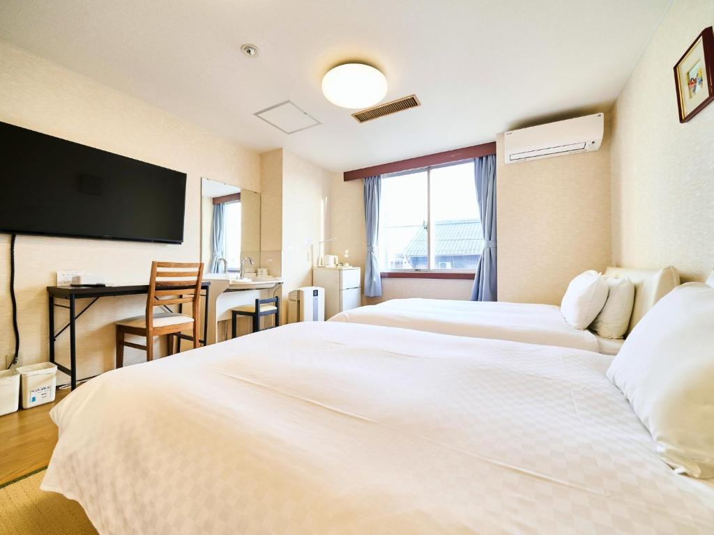 大垣Okasan Hotel - Vacation STAY 45150v的酒店客房设有两张白色的床和一张书桌