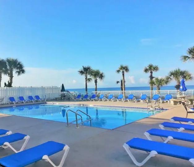 巴拿马城海滩Sunny Daze, Desirable Kid Friendly Resort, 3 minute walk to the Beach, Resort Beachside Pool & Restaurant的一个带蓝色椅子的游泳池以及大海