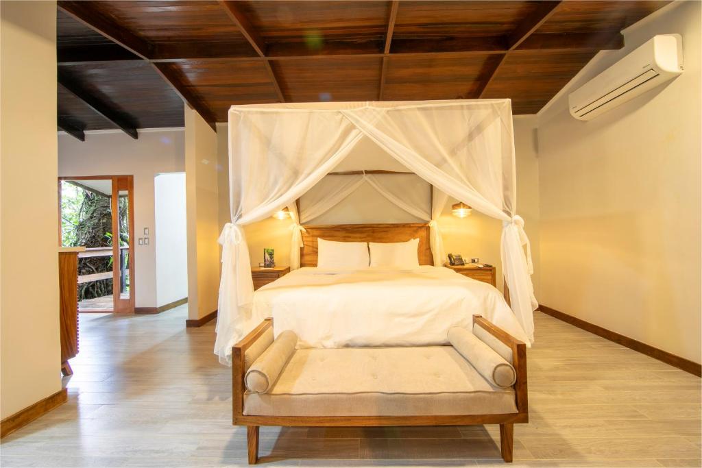 福尔图纳Chachagua Rainforest Hotel &amp; Hot Springs的一间卧室设有一张带木制天花板的天蓬床。