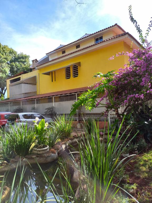 巴西利亚KzaZenDF CamaeCafé AsaSul的一座黄色的房子,前面有汽车停放