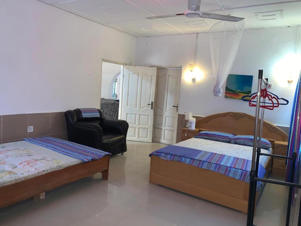 DompoasiInviting 3-Bed Apartment in Kumasi Ashanti Ghana的一间卧室配有两张床和椅子