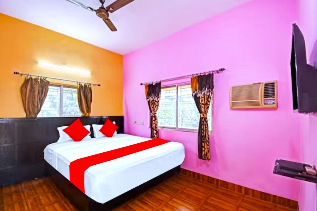 kolkataGoroomgo Salt Lake Palace Kolkata - Fully Air Conditioned & Parking Facilities的卧室拥有粉红色的墙壁,配有一张带红色枕头的床
