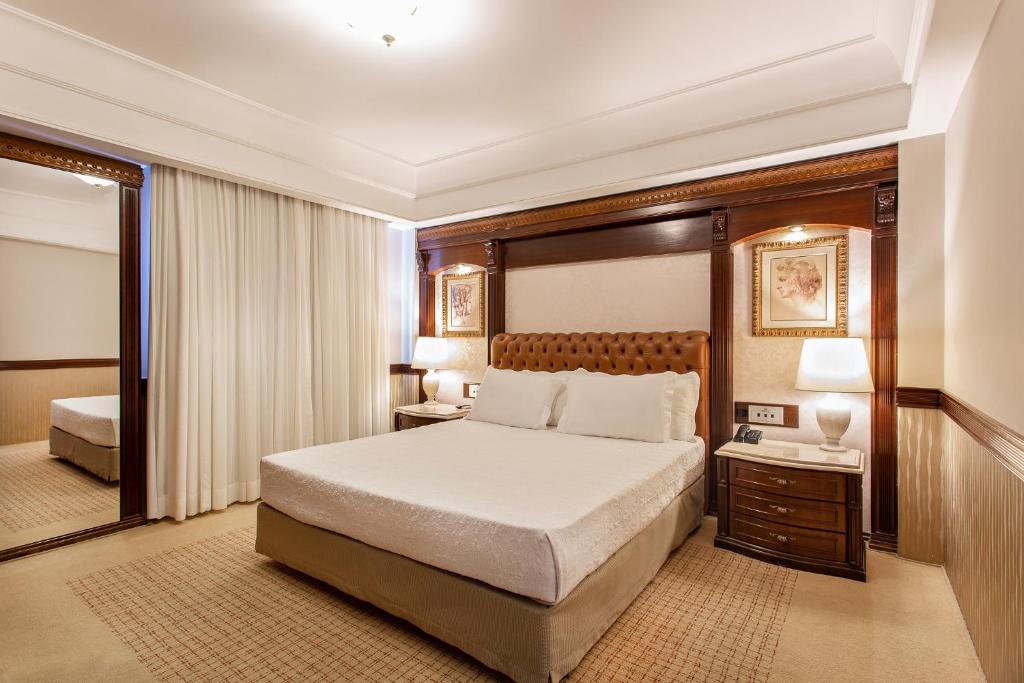 隆德里纳波旁隆德里纳商务酒店的酒店客房,配有床和镜子